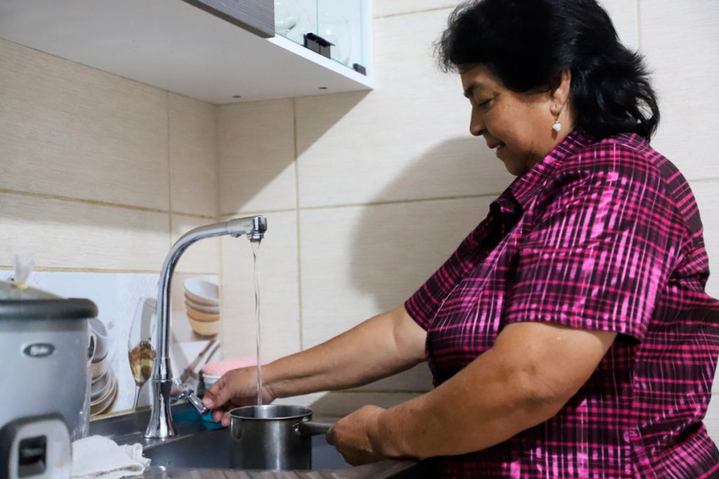 Mujer usando el lava platos para recoger agua