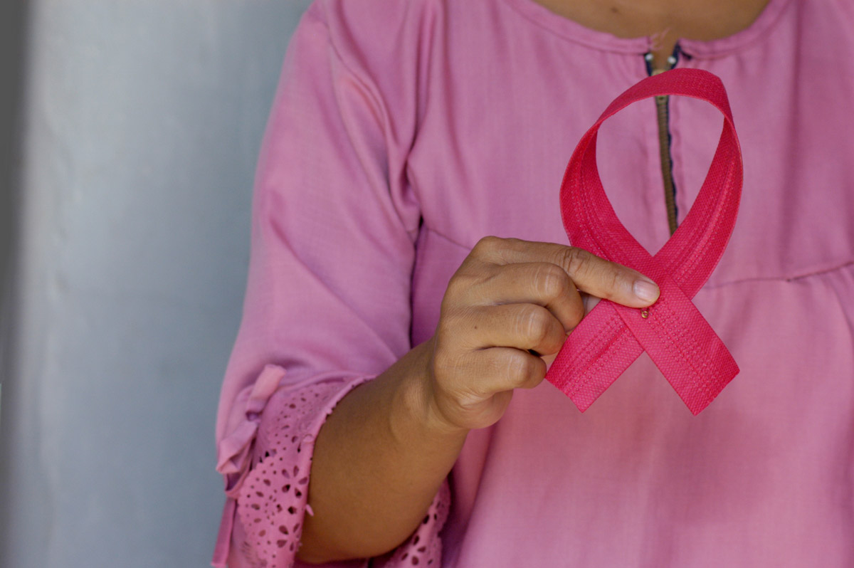 Mujer sostiene un lazo de conmemoración del cáncer de mama