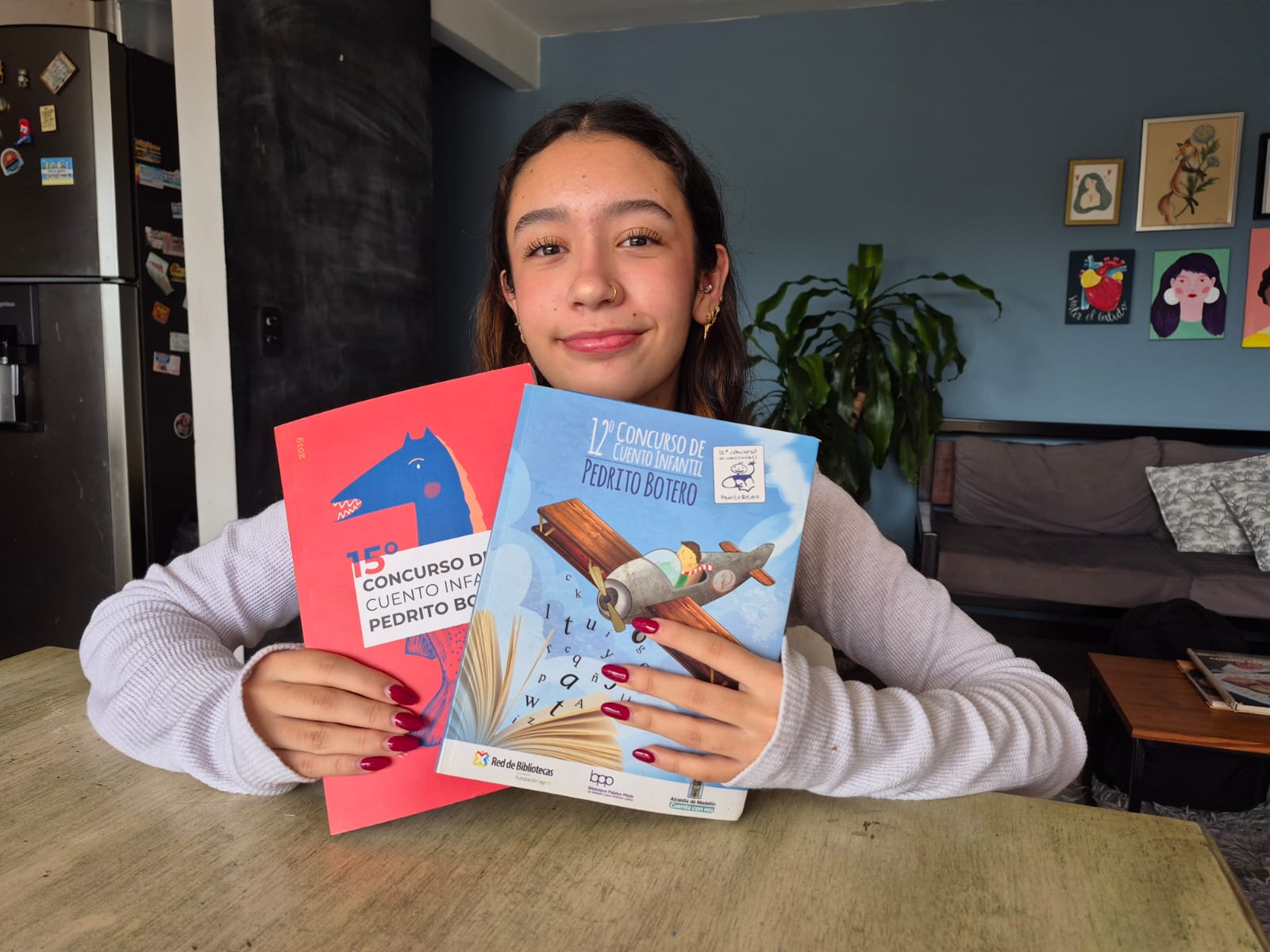 Luciana con los libros de los cuentos ganadores y finalistas del concurso en las ediciones de 2019 y 2016.