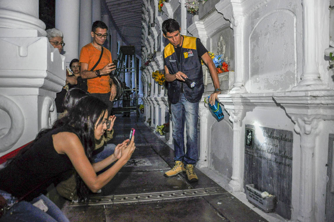 Imagen de una mujer tomando una foto de la tumba de Carlos Gardel